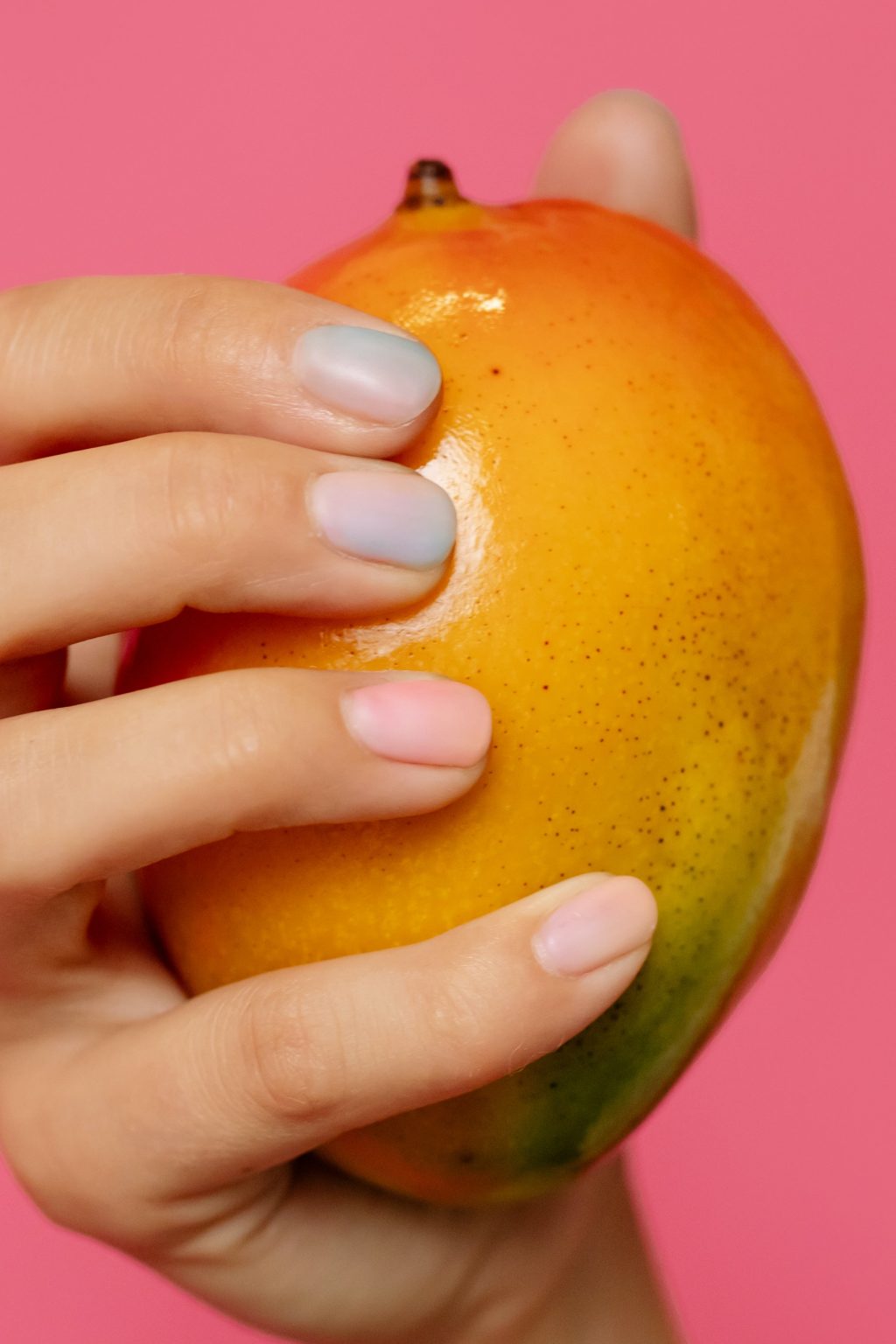 Over Mondial Food Solutions: mango in hand met gekleurde nagels op roze achtergrond